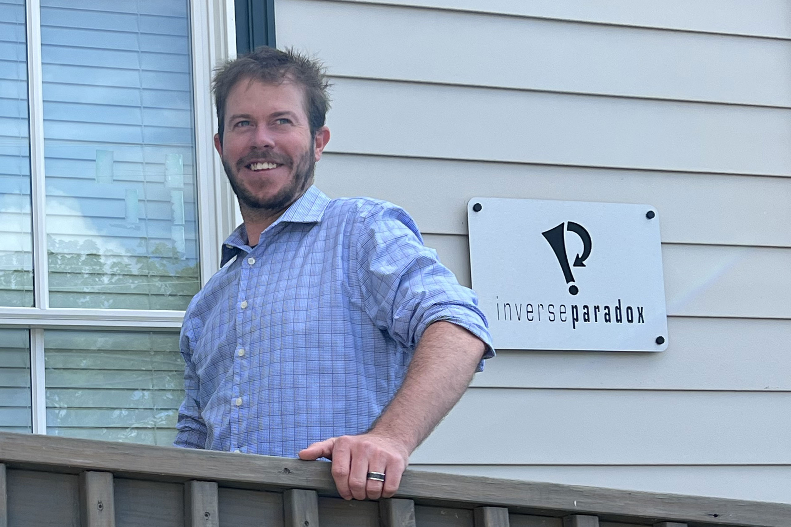 Ben smiling and standing in front of the Inverse Paradox sign